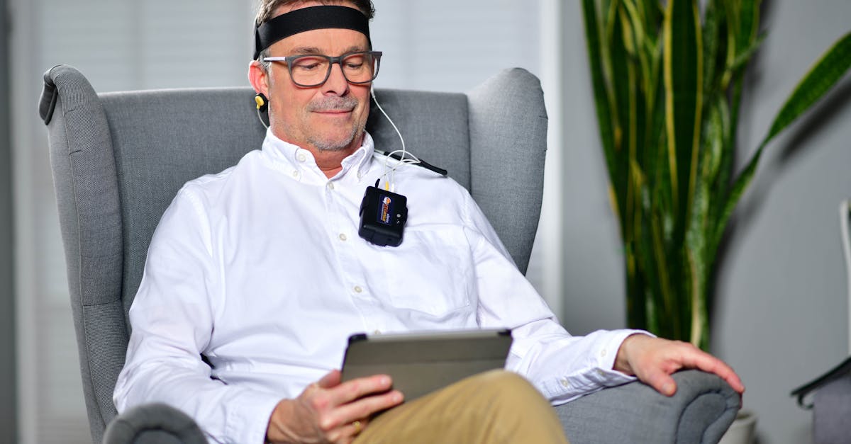 Man sitting in an armchair using a neurofeedback device, illustrating modern technology in healthcare.